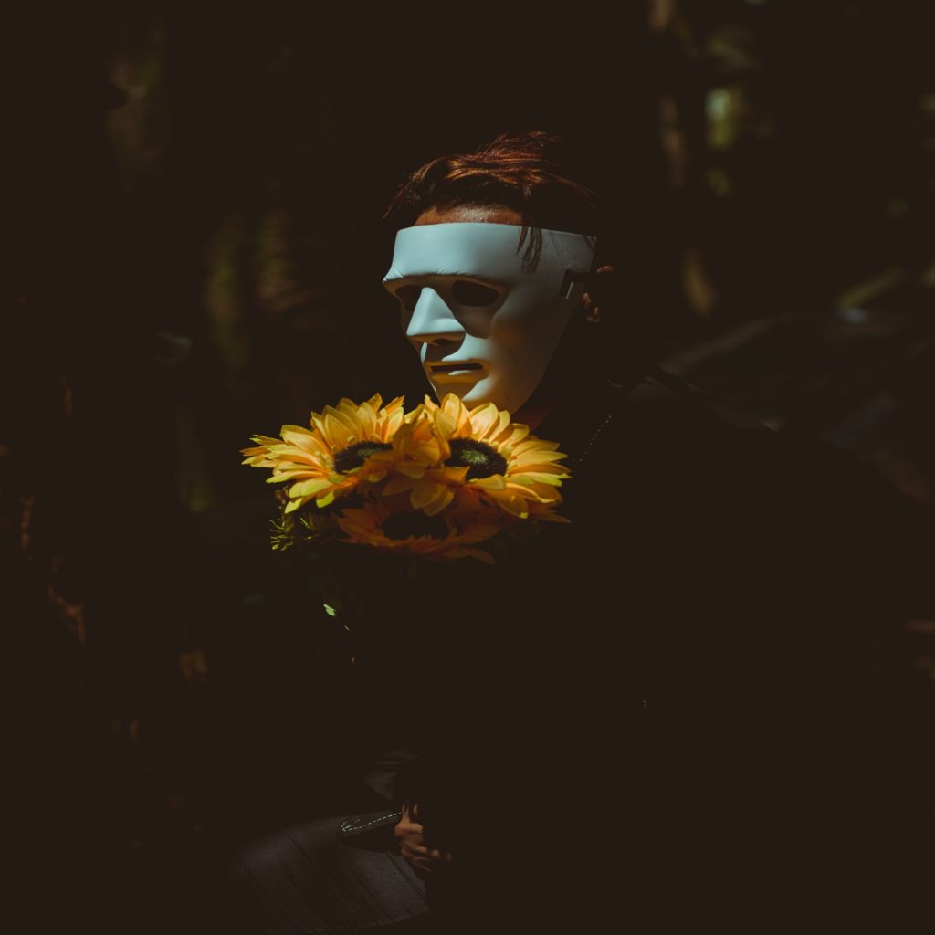 person wearing a mask holding sunflowers 2064756